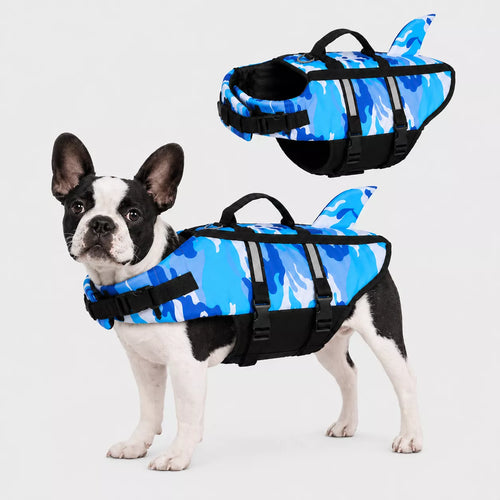 Dog wearing a blue camouflage life jacket with shark fin design on a light gray background
