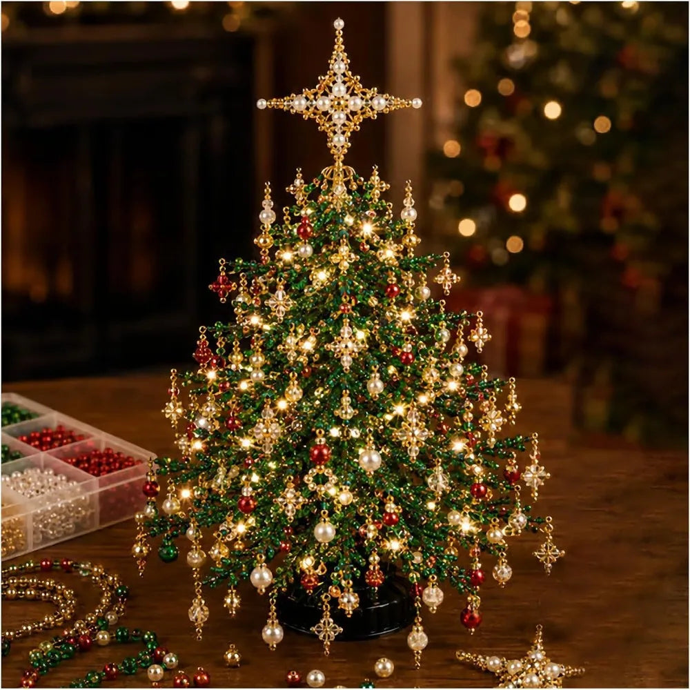 A decorated miniature Christmas tree with warm white lights, red and green ornaments, hanging gold star ornaments, and a large gold star topper, displayed on a wooden table with craft beads nearby.