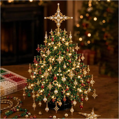 A decorated miniature Christmas tree with warm white lights, red and green ornaments, hanging gold star ornaments, and a large gold star topper, displayed on a wooden table with craft beads nearby.