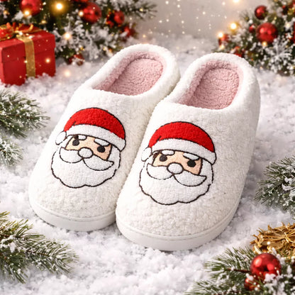 Christmas slippers with Santa face design on a snowy background with Christmas decorations.